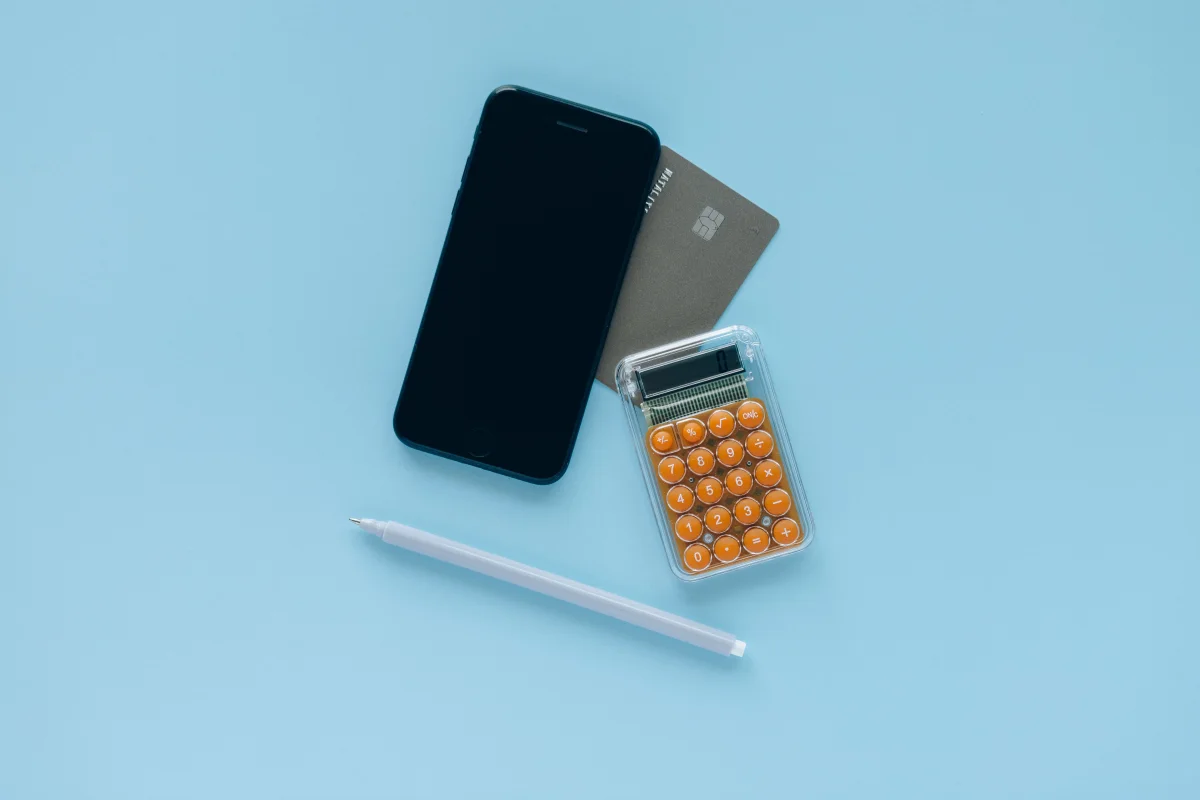 Smartphone, cartão e calculadora usados para conferir pagamentos
